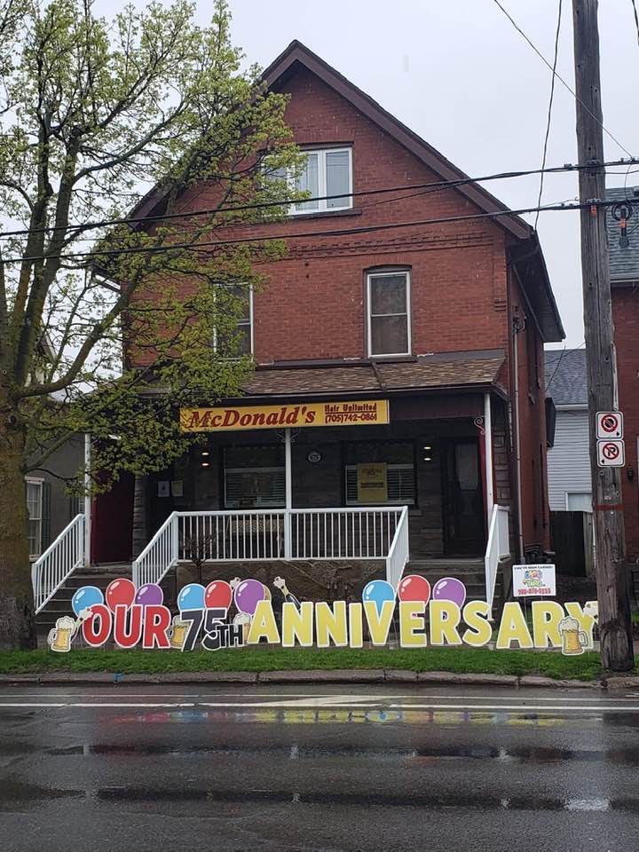 The McDonald's Hair Unlimited storefront with a giant 'Our 75th Anniversary' lawn display